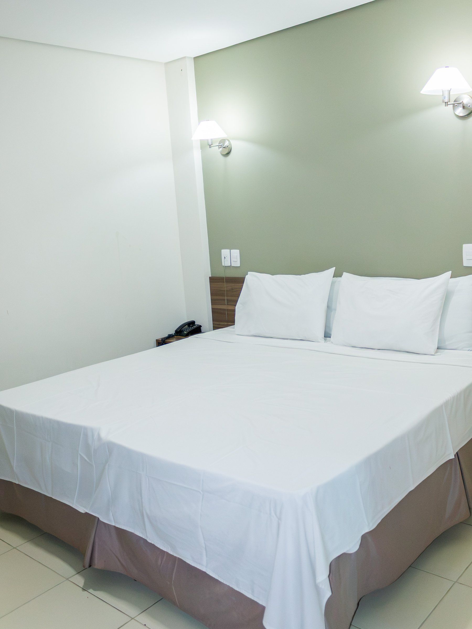 Deluxe Double room, double bed with a light green wall and two lamps