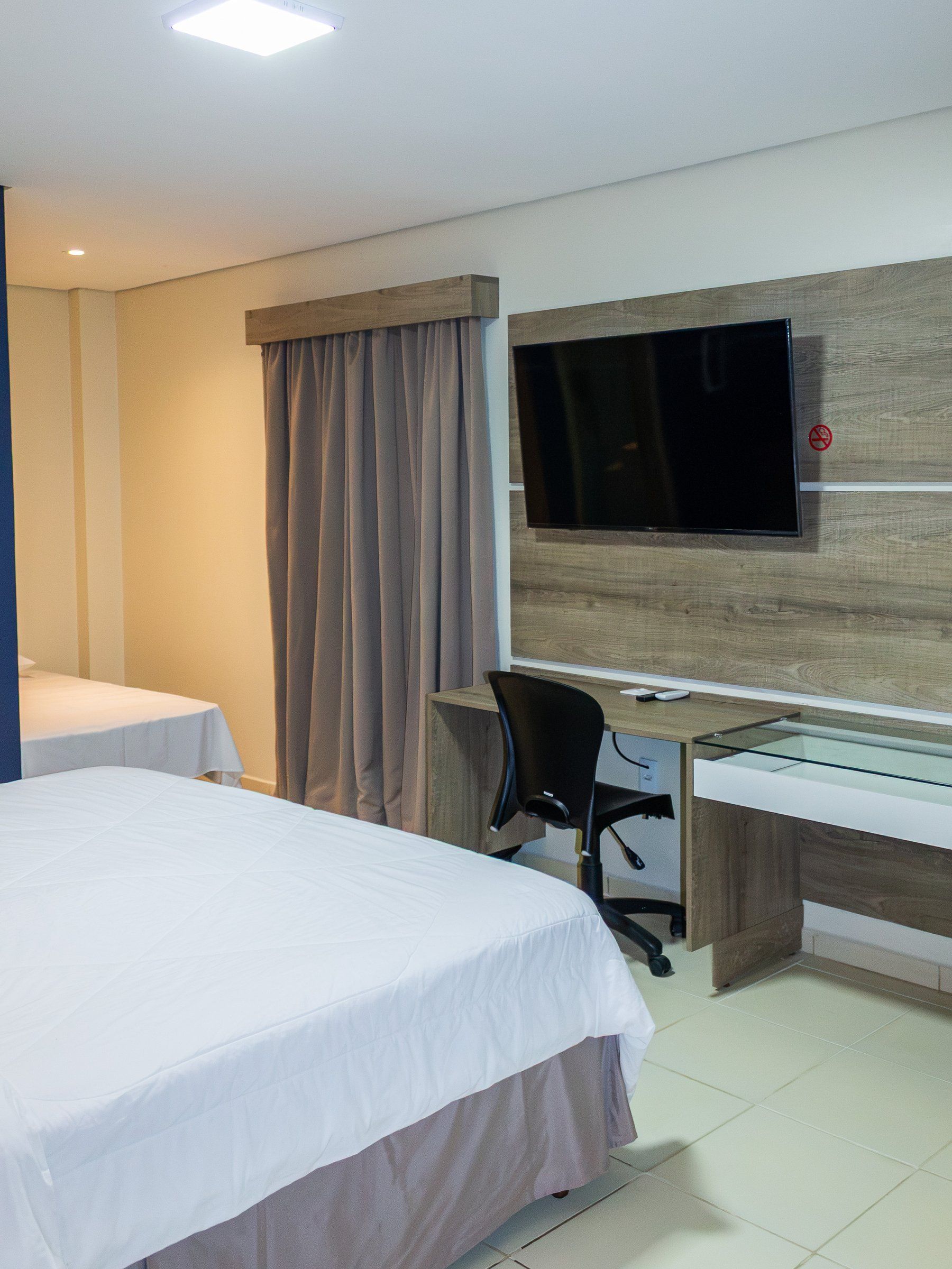 Deluxe Double room, bed, work desk and TV on the wooden panel