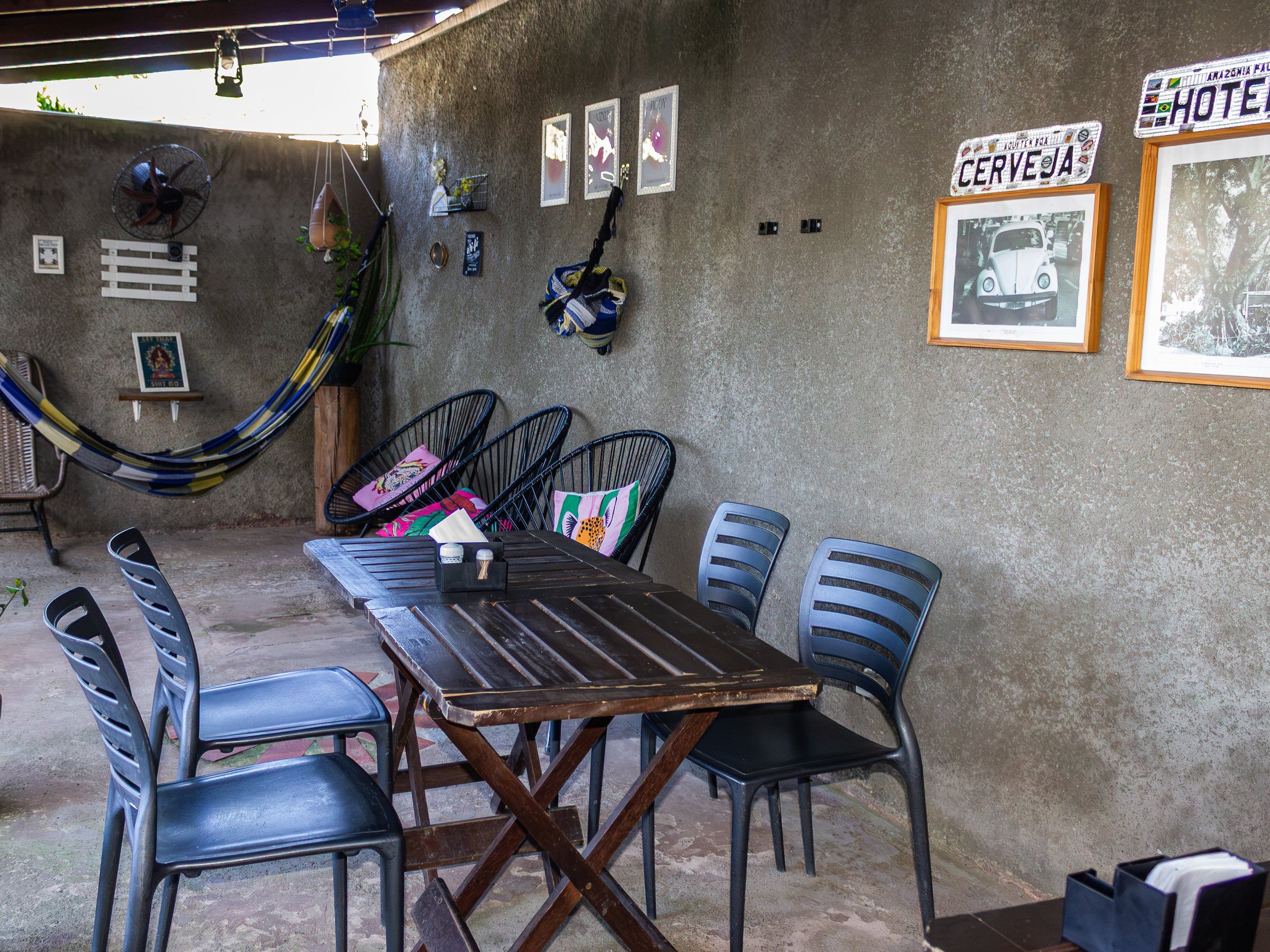 Covered veranda with wooden tables, chairs and a hammock